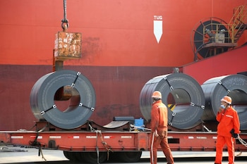 Trabajadores cargan productos de acero para su exportación a un buque de carga en un puerto de Lianyungang, provincia de Jiangsu, China.
