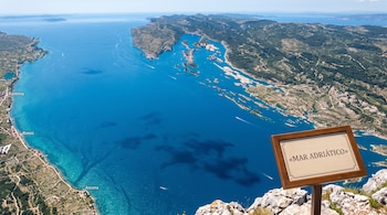 Vista aérea de un mar azul con nombres de ciudades impresos en la superficie y un cartel de madera que dice Mar Adriático.