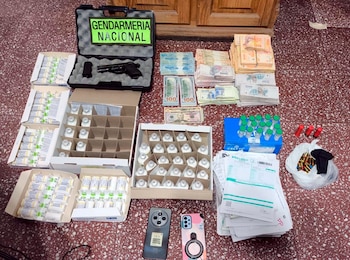 Vista aérea: Viales de propofol y otros medicamentos, fajos de dinero argentino y dólares, una pistola en estuche, municiones, y dos teléfonos celulares