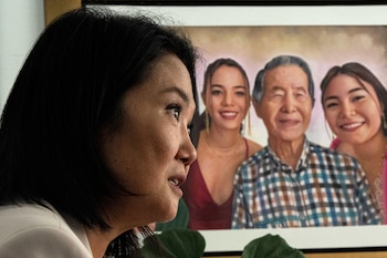 Primer plano del perfil derecho de Keiko Fujimori hablando, con un cuadro familiar detrás que muestra a un hombre mayor y dos mujeres jóvenes sonriendo