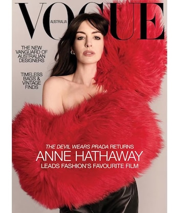 Anne Hathaway irrumpe en la portada de Vogue Australia envuelta en un abrigo de piel sintética rojo, con un hombro al descubierto y maquillaje neutro, en una imagen que fusiona presencia y vulnerabilidad (Vogue)