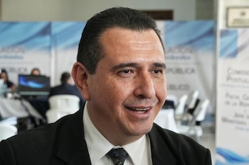 Primer plano del abogado Gabriel Estuardo García Luna, un hombre de mediana edad con cabello oscuro, sonriendo. Viste traje oscuro, camisa blanca y corbata estampada