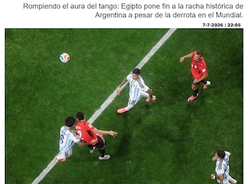 Campo de fútbol de césped verde con líneas blancas. Jugadores con camisetas blancas y celestes, y jugadores con camisetas rojas. Un balón de fútbol