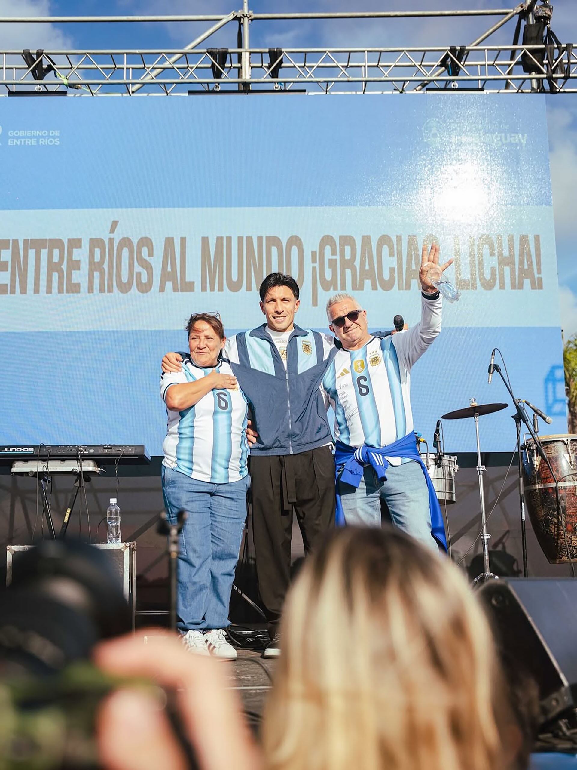 El futbolista Lisandro Martínez, con camiseta de la selección argentina, posa junto a sus padres en un escenario durante un evento en la provincia de Entre Ríos, Argentina.