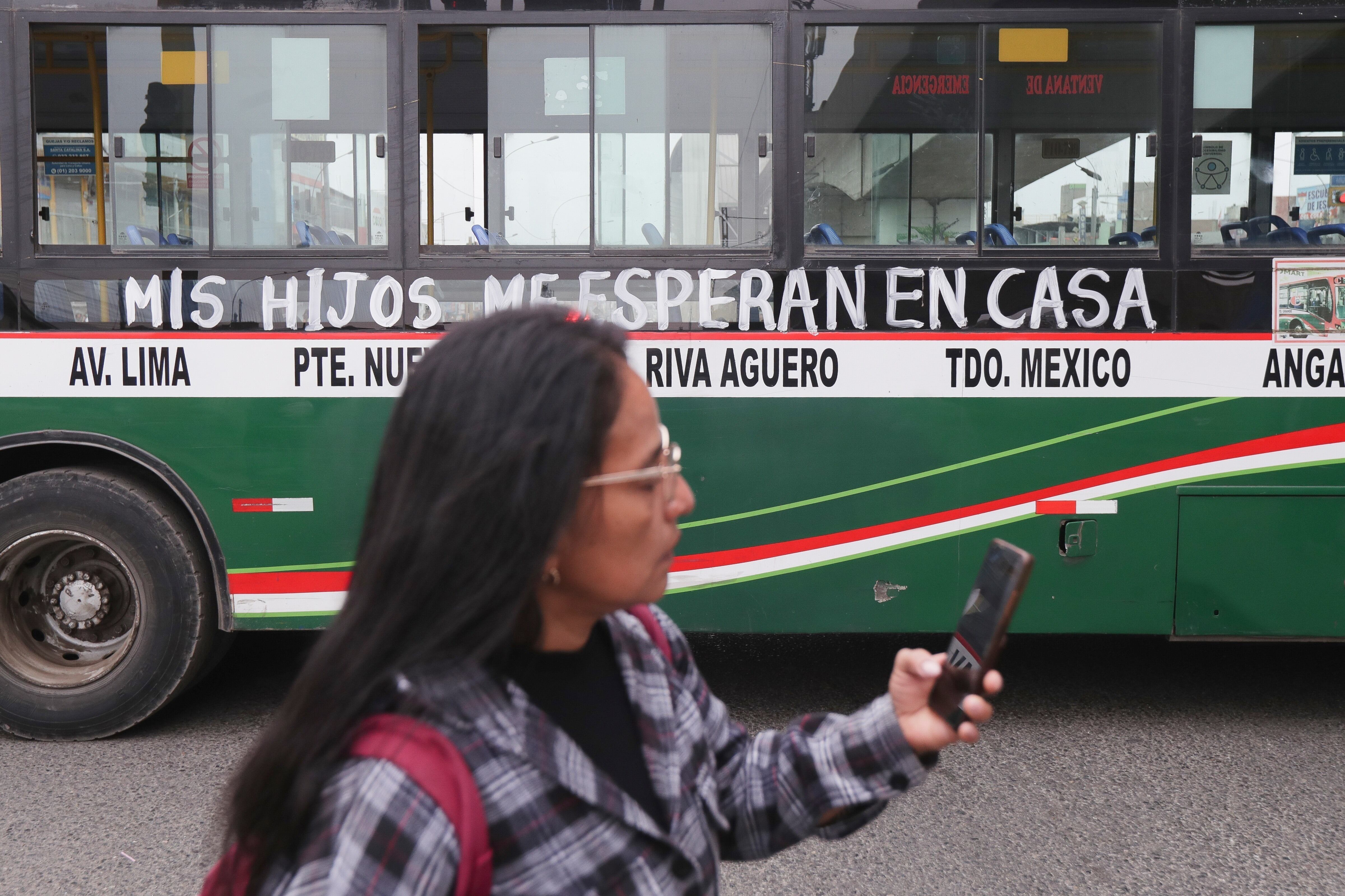 Una mujer pasa junto a un autobús con la leyenda