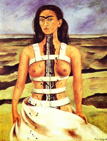 Retrato de una mujer con un corsé blanco, clavos en la piel y una columna de piedra fracturada en su torso ante un terreno desértico