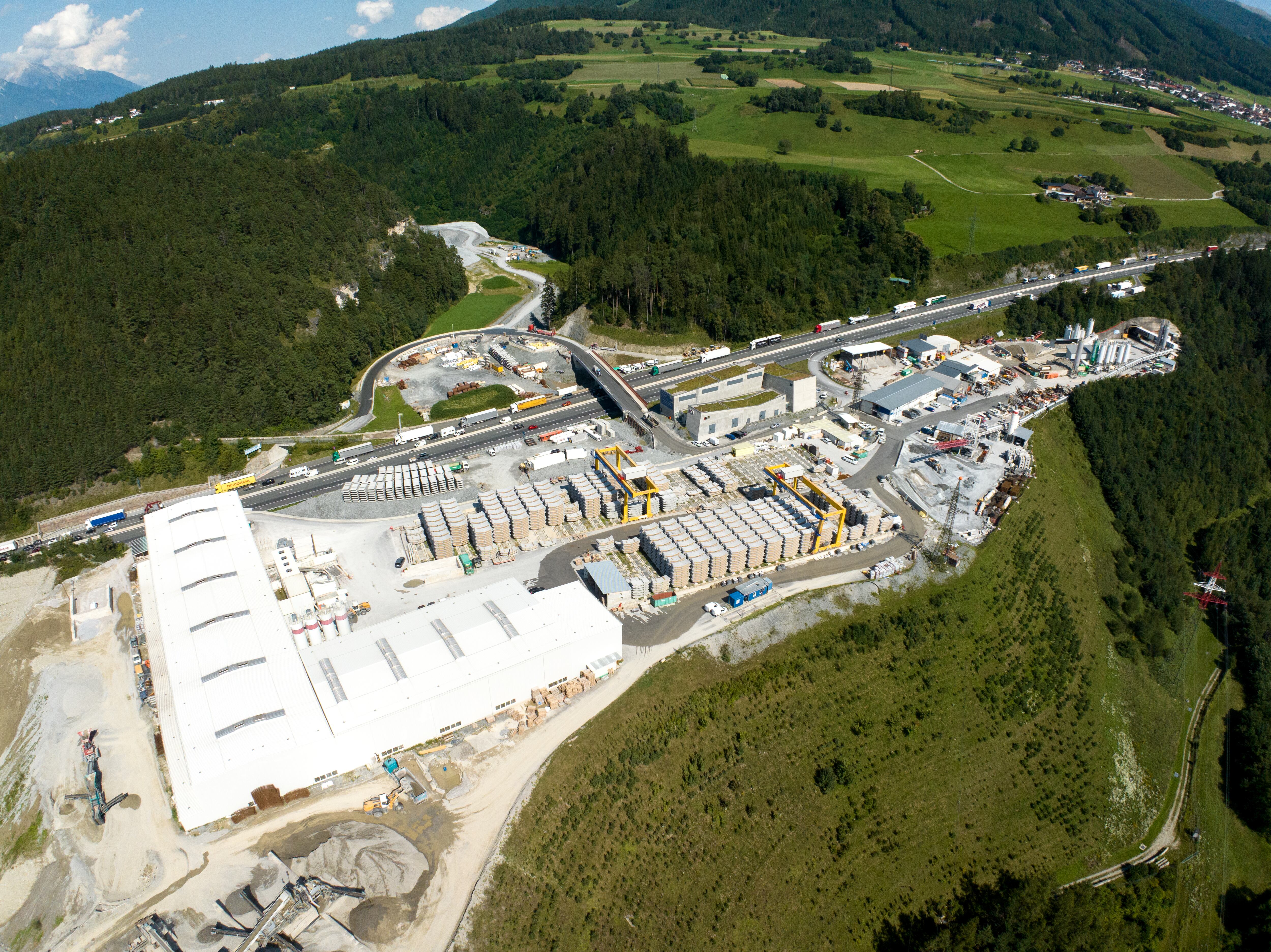 Vista aérea del extenso sitio de construcción del Túnel de Base del Brennero, mostrando la producción de segmentos prefabricados de concreto y la logística en el valle alpino (© BBT SE)