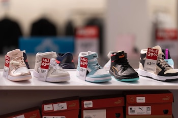 Varios pares de zapatillas Puma de caña alta en diferentes colores con etiquetas de precio de oferta en un estante. Cajas de zapatos