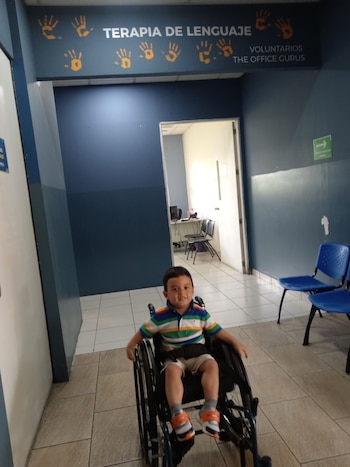 André puede caminar con ayuda durante períodos cortos, pero utiliza silla de ruedas para trayectos largos debido a las dificultades de movilidad asociadas a la enfermedad. (Foto cortesía familia Rivera Escamilla)
