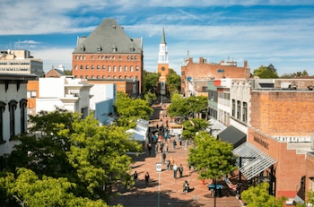 Vista aérea de una calle peatonal adoquinada, Church Street Marketplace, con edificios de ladrillo y blancos, árboles verdes y mucha gente caminando