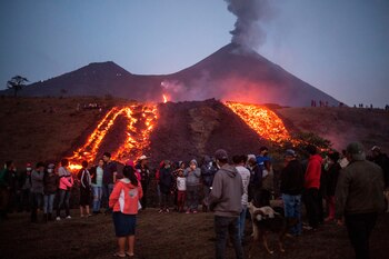 Personas se agrupan alrededor de uno de los ríos de lava causados por el volcán de Pacaya, el 13 de abril de 2021 en la aldea El Patrocinio de San Vicente Pacaya (Guatemala). EFE/Esteban Biba