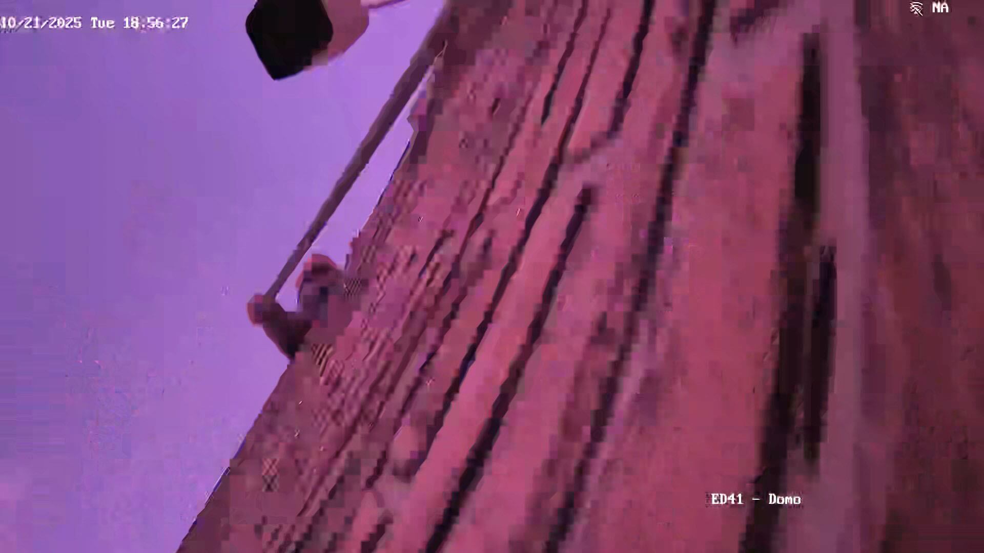 Una persona con la cara tapada rompe una cámara del predio del INTI