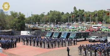 Cientos de policías con equipo antidisturbios, escudos y cascos azules, formados frente a autobuses y patrullas, con aficionados y coches al fondo