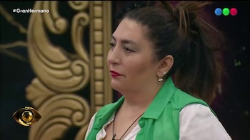 Mujer con chaleco verde y camisa blanca con una lágrima en la mejilla. Fondo oscuro con decoración dorada. Logos de Gran Hermano y un ojo en pantalla