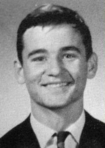 Fotografía en blanco y negro de un hombre joven sonriendo, de frente, con pelo corto, chaqueta, camisa y corbata