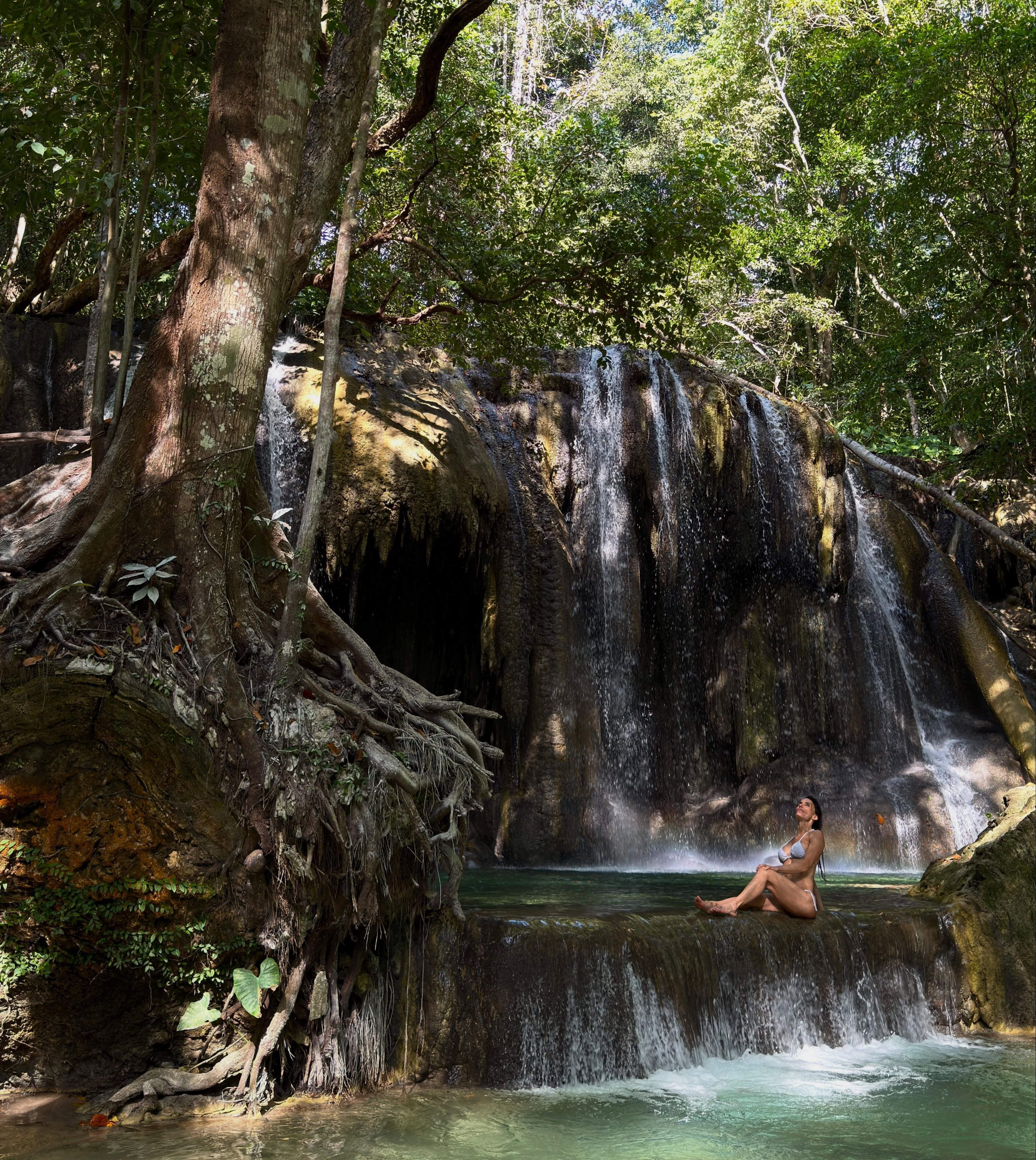 María Susini permanece sentada junto a una cascada en un entorno natural durante sus vacaciones en Indonesia