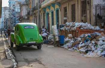 Un automóvil clásico pasa junto a basura acumulada en una calle de La Habana (Foto AP/Ramón Espinosa)