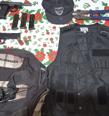 Dos pistolas, tres cargadores, dos cartuchos, un chaleco negro, una gorra, una mochila y un cortapernos sobre una mesa