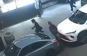 Captura de video de seguridad desde un plano cenital con peatones caminando entre dos automóviles en una calle urbana