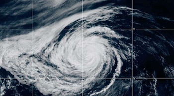 Imagen satelital en espiral de una tormenta sobre el océano con líneas blancas de coordenadas geográficas