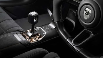 Interior de auto con palanca de cambios manual de seis velocidades, consola central de fibra de carbono, volante con logo MCL GGT, asiento tapizado