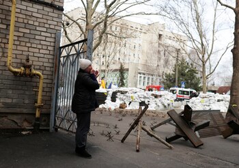 Una mujer llora mientras espera noticias sobre sus familiares frente a un edificio gubernamental destruido en Mykolaiv (Reuters)