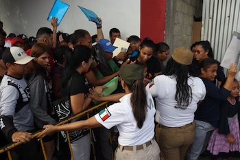 Personas migrantes hacen fila para