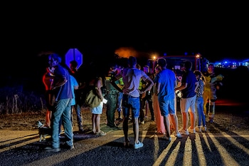 Varias personas observan las lamas del Incendio forestal declarado ayer tarde en el paraje Raboconejo de Niebla (Huelva). (EFE/David Arjona)