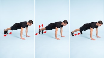 Un hombre en ropa deportiva negra realiza el ejercicio plank jack en tres paneles con flechas rojas que indican la dirección del movimiento de los pies.