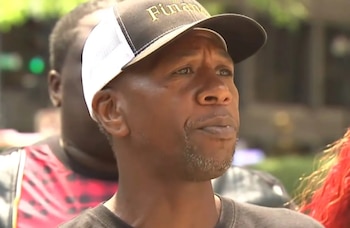 Primer plano de un hombre afroamericano con barba de chivo gris, vistiendo una gorra negra y blanca, mirando hacia la derecha con una expresión seria