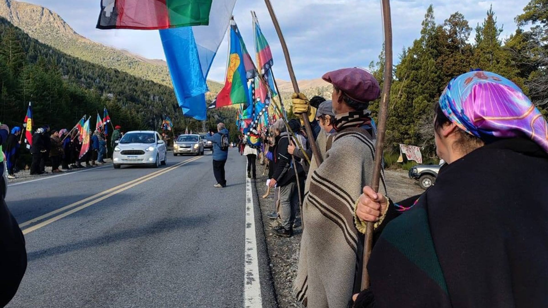 Miembros de la comunidad Mapuche de Neuquén se manifiestan a la vera de una ruta patagónica, ondeando banderas en protesta contra un desalojo.