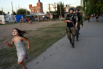 Una niña corre mientras agentes