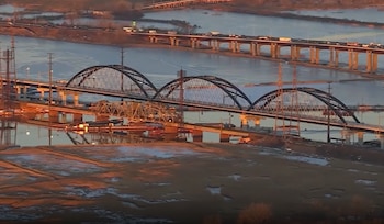 Vista aérea de puentes de estructura metálica y arcos que cruzan un río rodeado de vegetación y terrenos anegados