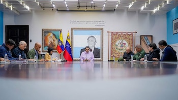 Vista amplia de una sala de reuniones con Nicolás Maduro al centro de una mesa larga, rodeado de funcionarios; retratos de Néstor Kirchner, Chávez y Bolívar detrás