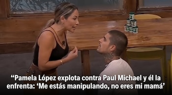 Pamela López, vestida de negro, confronta a Paul Michael, quien la mira desde abajo. Ambos están en un interior con una mesa de madera y frascos verdes.