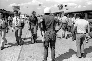 Carlos Alberto Reutemann camina por los boxes y es custodiado por un soldado (Gentileza Alejandro de Brito)