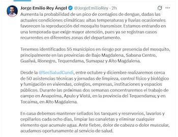 Tres mujeres con mascarillas y carpeta de apuntes entregan un paquete a un hombre mayor en la entrada de una casa de piedra