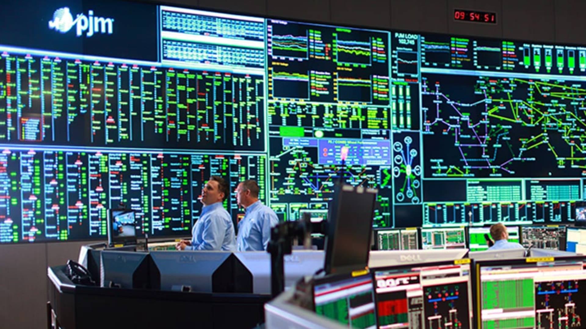 Operadores de PJM monitorean el rendimiento y la distribución de la red eléctrica a través de múltiples pantallas en un centro de control de energía, gestionando la estabilidad del sistema (PJM Interconnection)