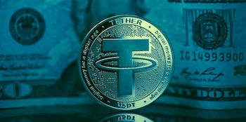 Primer plano de una moneda plateada de Tether (USDT) con el logo "T" y texto descriptivo, sobre un fondo borroso de billetes de dólar estadounidense en tonos fríos