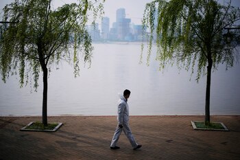 A man wearing protective gear walks by the Yangtze river in Wuhan, Hubei province, as China holds a national mourning for those who died of the coronavirus disease (COVID-19), on the Qingming tomb-sweeping festival, April 4, 2020. REUTERS/Aly Song