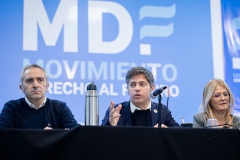 Hombre habla a micrófono, flanqueado por otro hombre y una mujer. Fondo azul con 'MD MOVIMIENTO DERECHO AL FUTURO'. Termo y mate en mesa