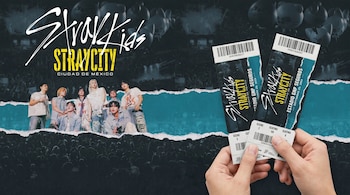 Primer plano de dos manos sosteniendo boletos de concierto de Stray Kids con el logotipo 'STRAYCITY CIUDAD DE MÉXICO', el grupo y una multitud al fondo.
