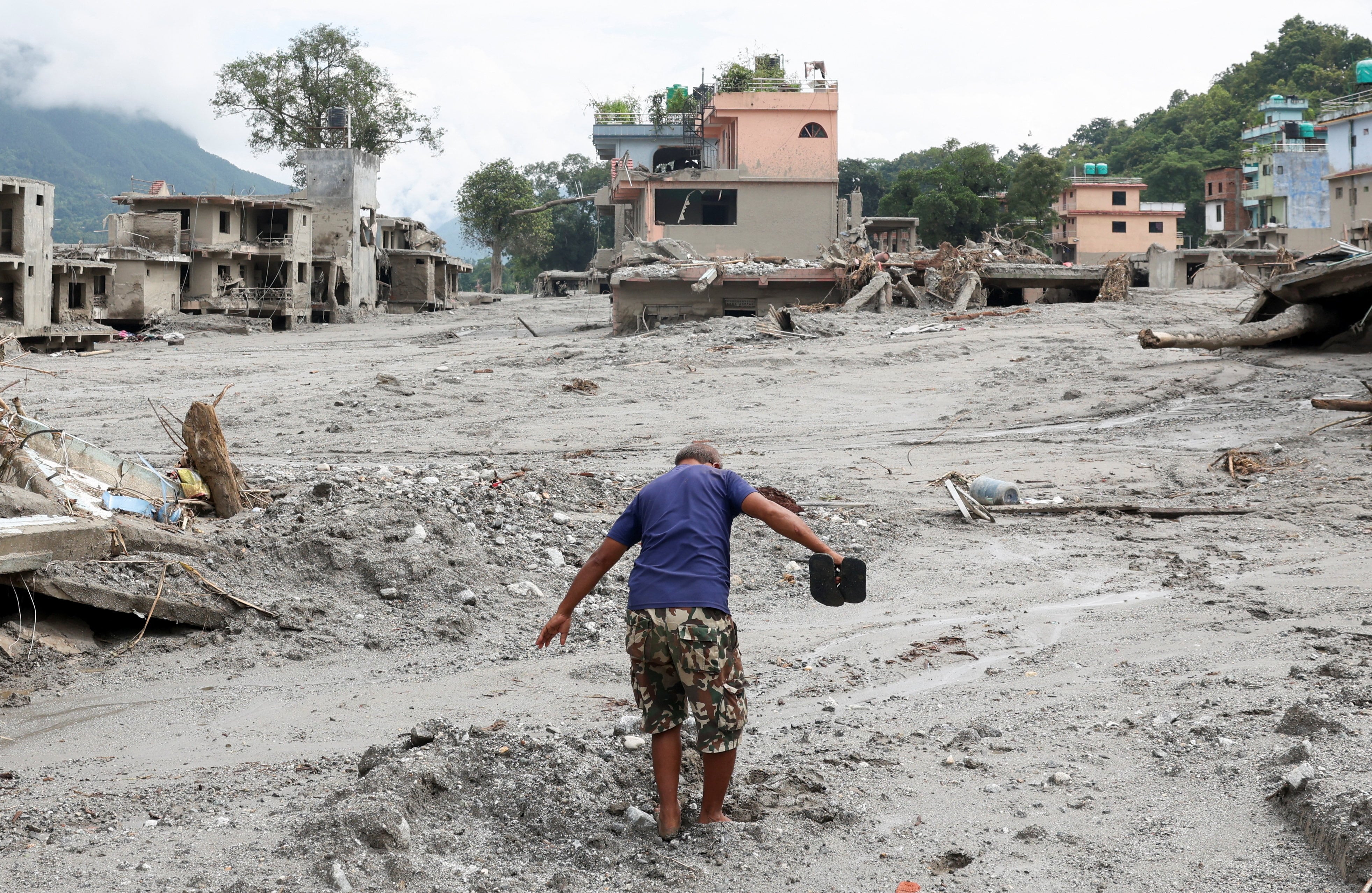 Un hombre avanza por una calle cubierta de barro junto a casas dañadas tras las inundaciones repentinas y el deslizamiento de tierra en Devighat, distrito de Nuwakot, Nepal, el 29 de agosto de 2026 (REUTERS/Adnan Abidi)
