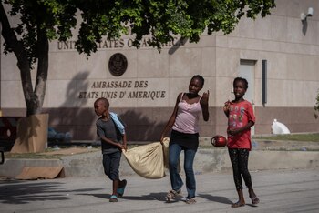 Personas caminan frente a la embajada de Estados Unidos, en Puerto Príncipe (EFE/Johnson Sabin)