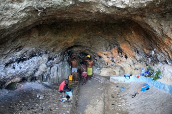 Varias personas se bañan y hacen la colada dentro de una cueva con un riachuelo ante la ausencia de agua corriente en sus casas, en Puerto Príncipe, Haití, el 21 de marzo de 2023. (AP Foto/Odelyn Joseph)