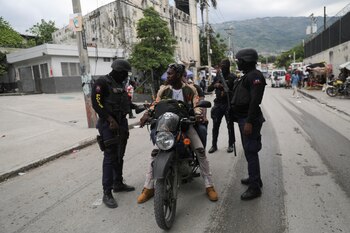 Police officers inspect people riding on a motorcycle to ensure no one carries weapons, in Port-au-Prince, Haiti May 24, 2024. REUTERS/Ralph Tedy Erol