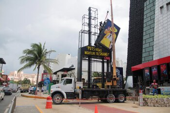 Trabajadores desarman un letrero luminoso