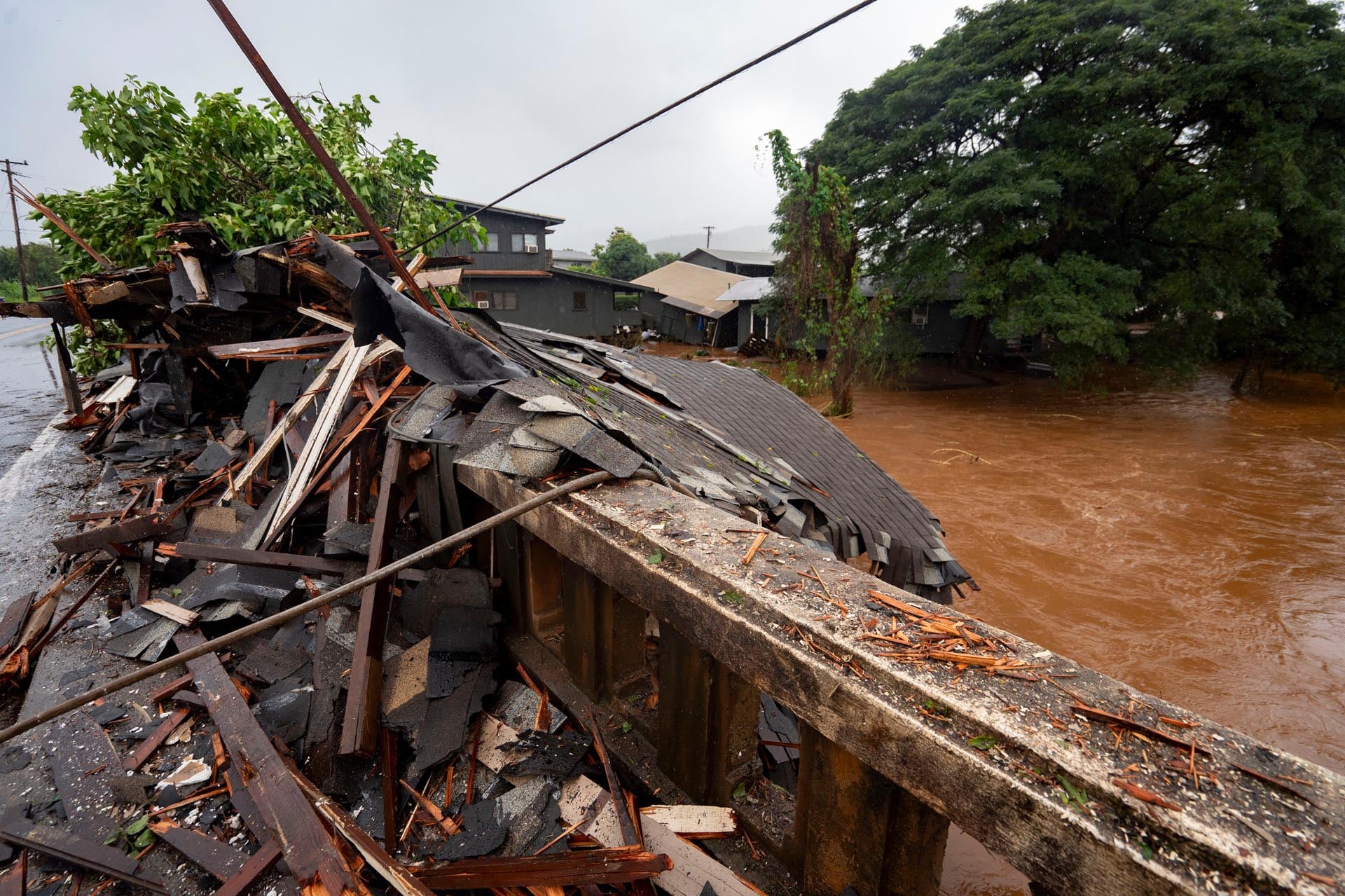 Escombros de una estructura se acumulan sobre un puente mientras el agua de las inundaciones, provocadas por las peores lluvias en 20 años, fluye a través de un río desbordado en Hawái.