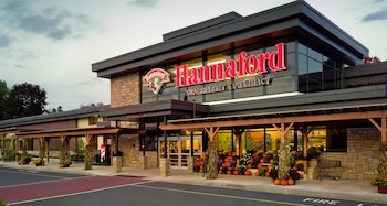 Fachada de un supermercado Hannaford con letrero luminoso, grandes ventanales, columnas de piedra y calabazas decorativas en la entrada