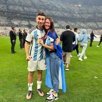 Gonzalo Montiel, con camiseta de Argentina y medalla de oro, abraza a Karina Nacucchio, quien llora de emoción en un campo de fútbol